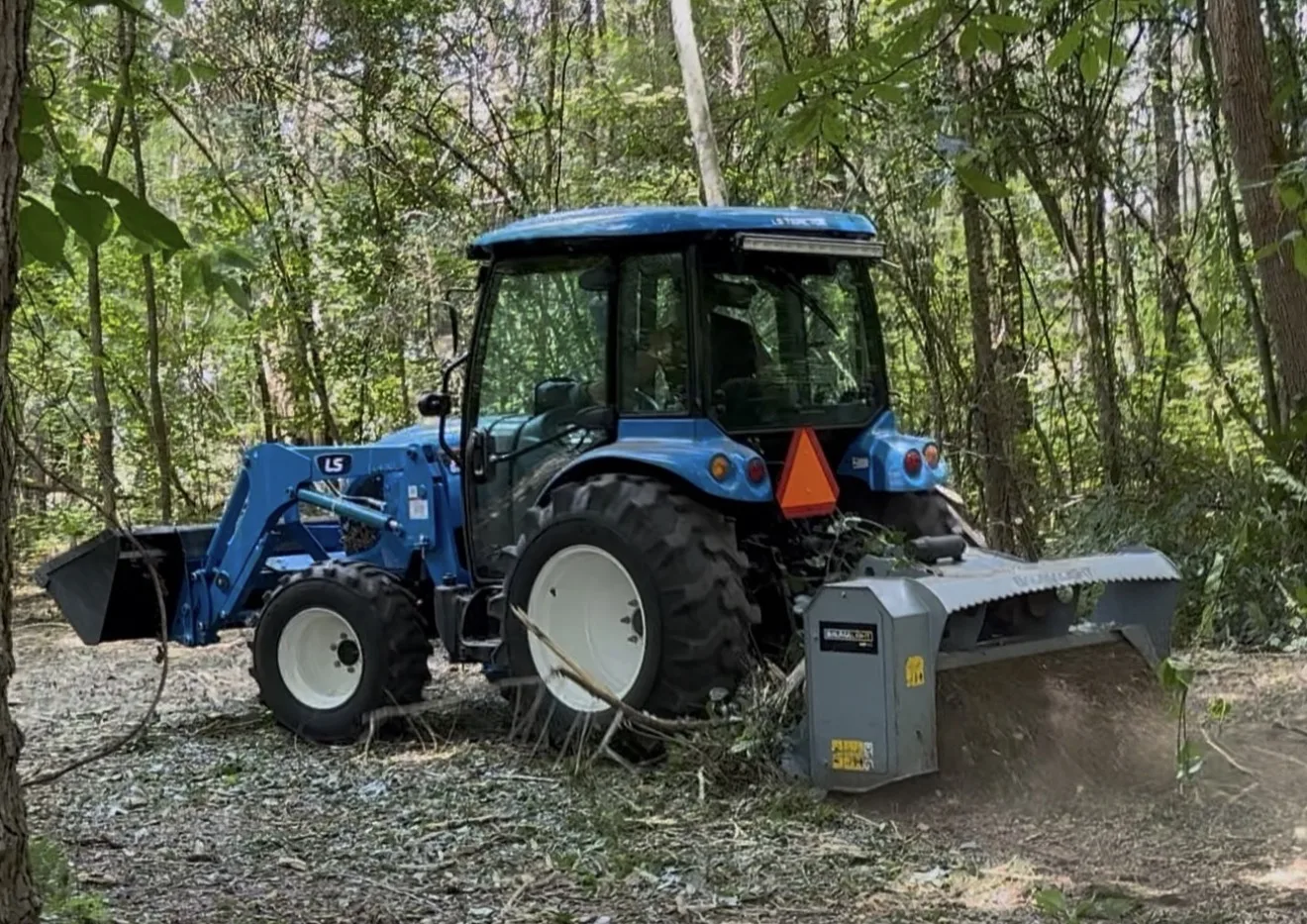 LS tractor with Baumalight forestry mulcher working in the woods